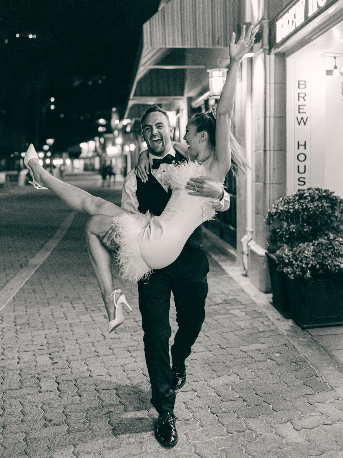 Groom walks with bride in his arms and both are happy and are having fun