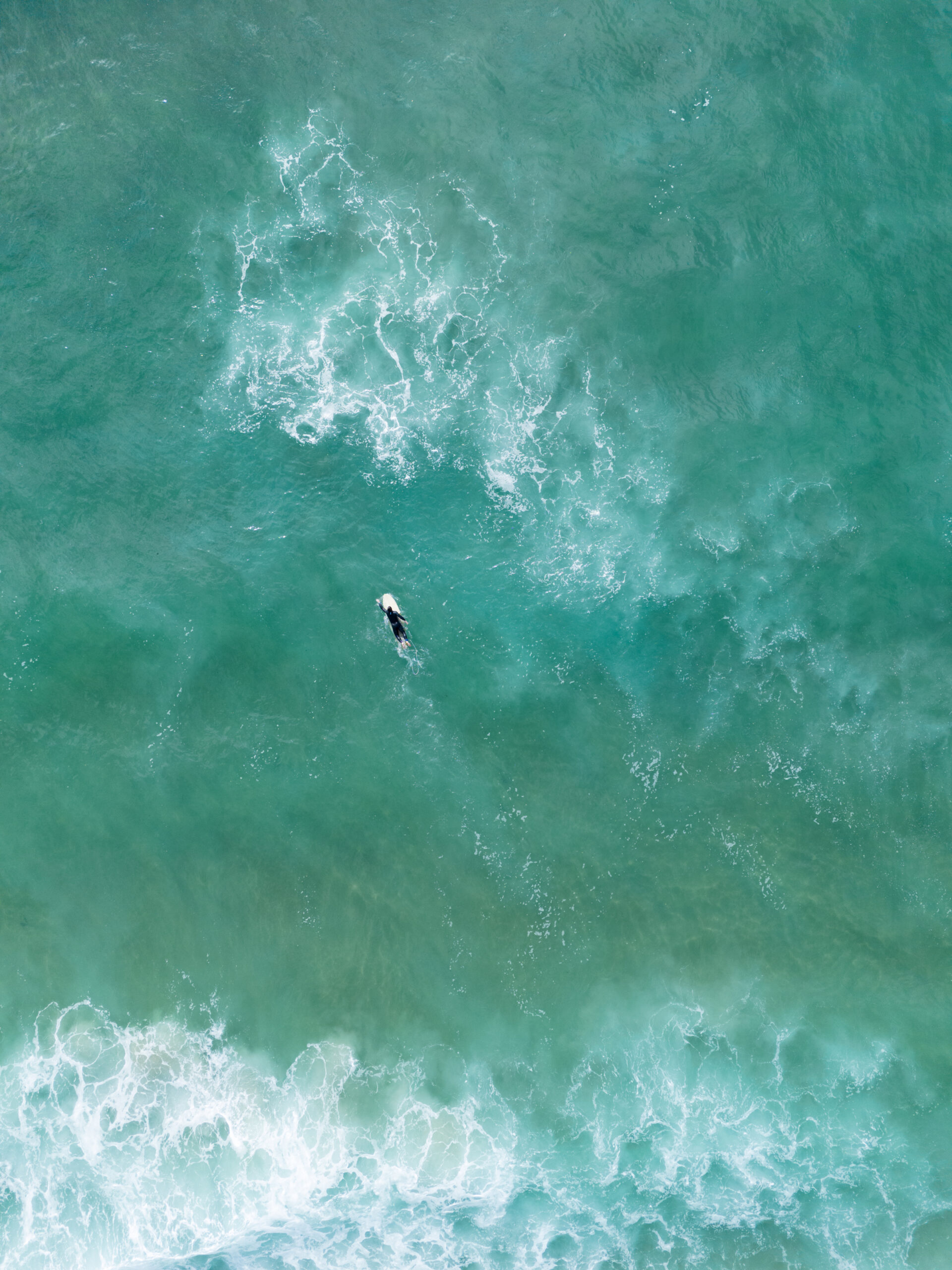 Aerial shot of the ocean with surfer